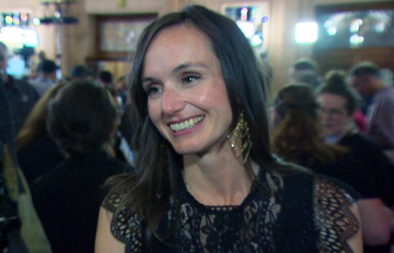 A woman smiles and talks to a reporter. 