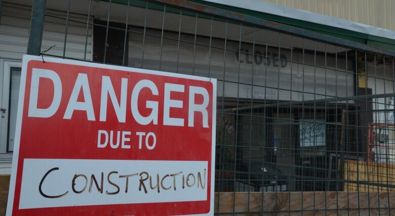 Construction fencing in front of an old cinema with 'Closed' on the marquis and a 'Danger due to construction' sign in the foreground