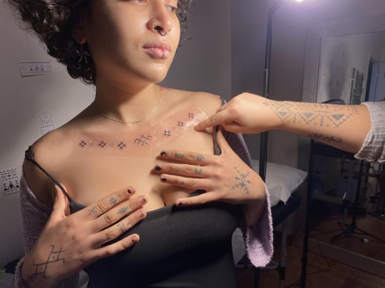 A woman shows a new tattoo on her collar.