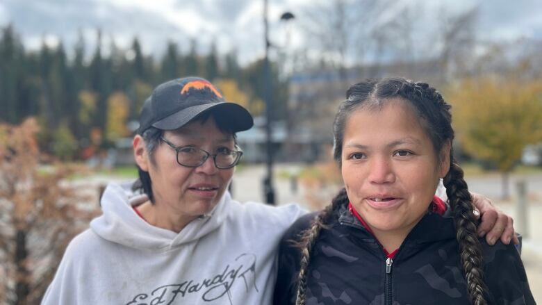 Two women stand in front of a blurred background