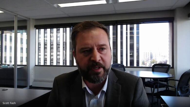 Scott Fash, executive director of Alberta's Building Industry and Land Development Association, sits in an office. He wears a suit and has a goatee.