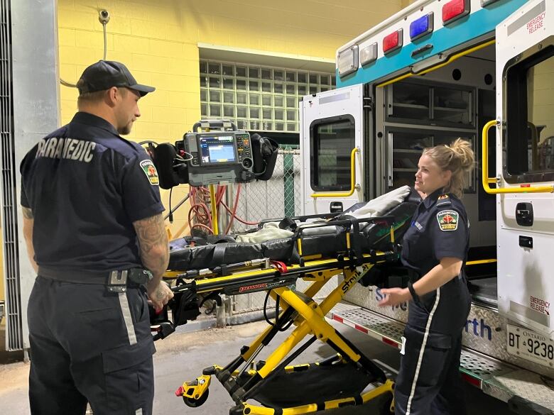 Two paramedics unload a stretcher from an ambulance.