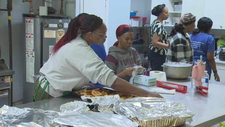 People help prepare food in a kitchen.