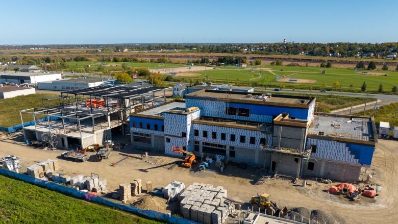 Piles of material and equipment surround a semi-complete two-storey building.