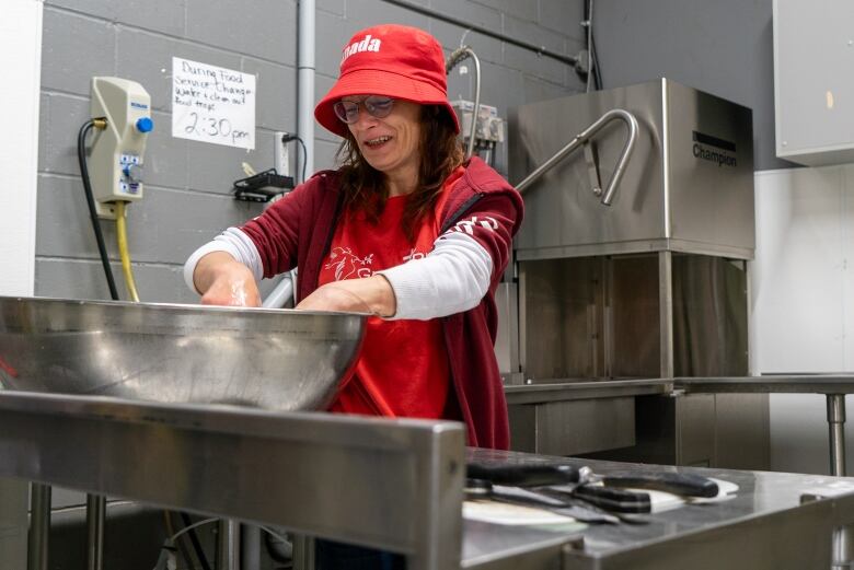 A woman dips her hands in a large bowl of soapy water.