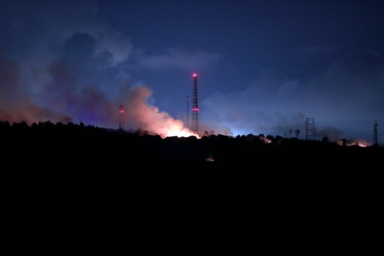 A fire burns on a ridge at night.