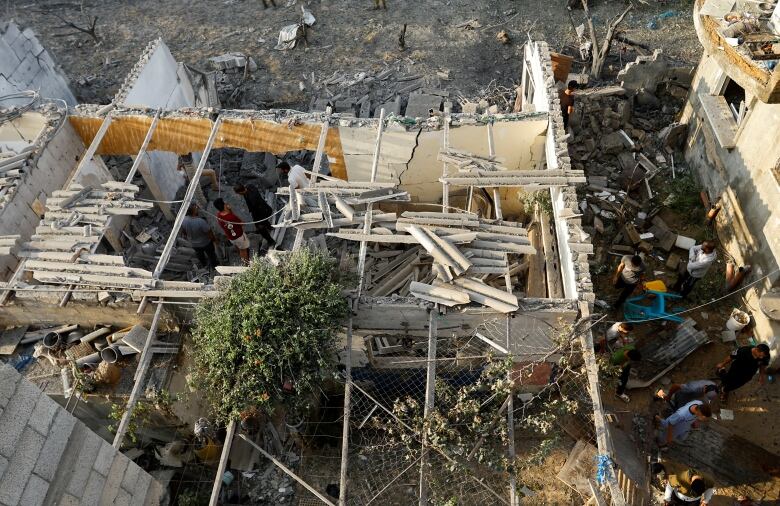 Palestinians inspect damage to a ruined a house hit by Israeli strikes.