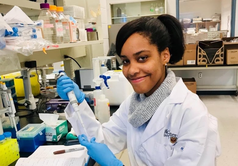 A woman in a lab coat smiles. 