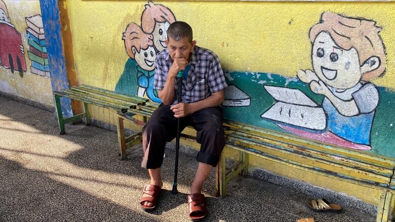 A man with a cane sits on a bench