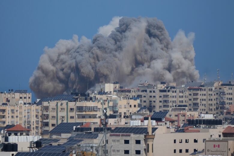 A massive cloud of dust and smoke rises from an airstrike in an urban centre.