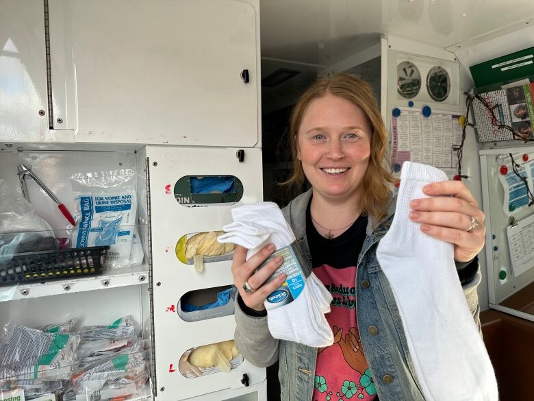 A nurse is shown holding up several pairs of white socks in the back of a mobile medical treatment van in Halifax.