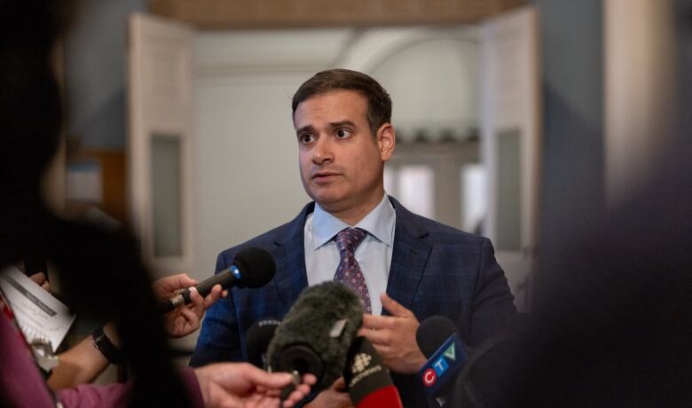 A man stands in front of microphones.