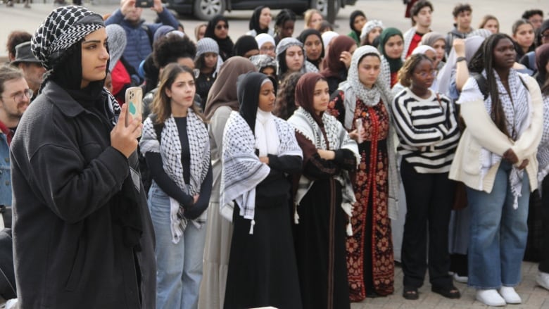 A crowd gathers outside a university for a memorial.