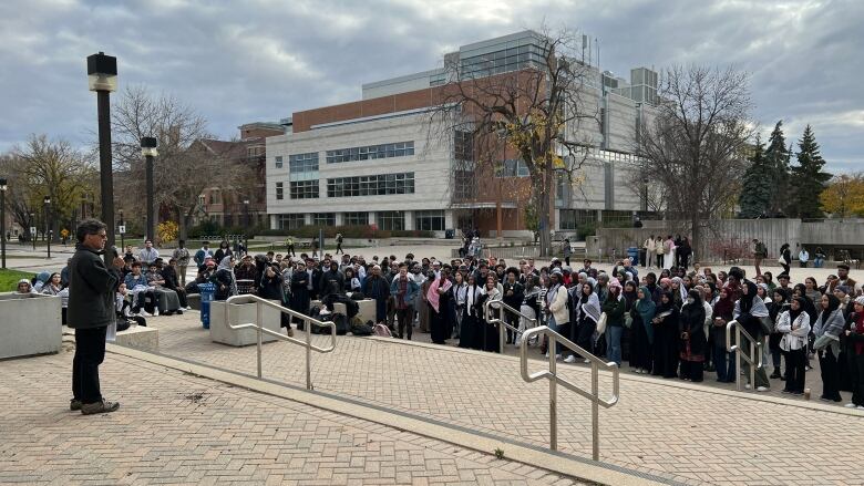 A crowd gathers outside a university for a memorial.