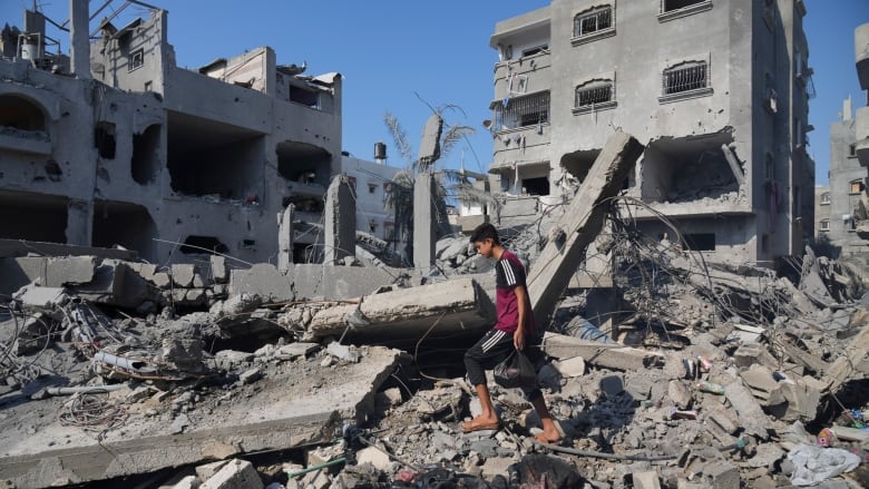 A young man walks through a ruined building. 