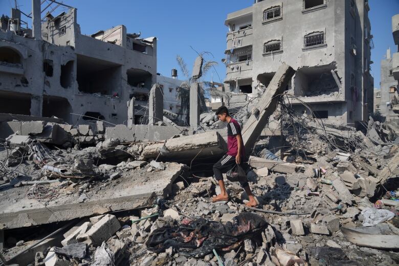 A young man walks through a ruined building. 