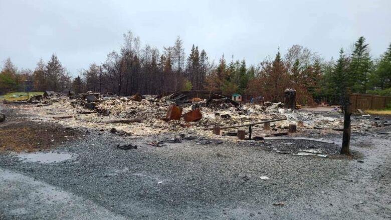 a pile of burned debris in a wood area. 