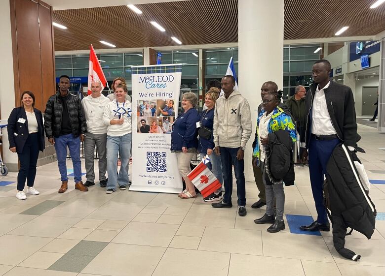 People stand next to a banner with Canadian and Nova Scotian flags.