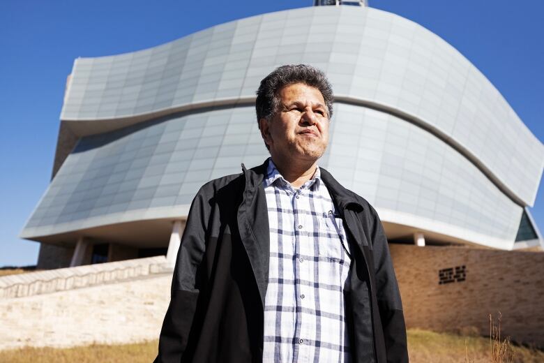 A man wearing glasses and a jacket is seen standing outside Canadian Museum of Human Rights in Winnipeg.