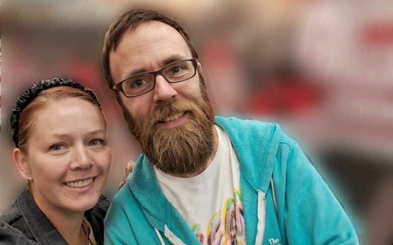 A woman with red hair and a man with a beard smile for the camera