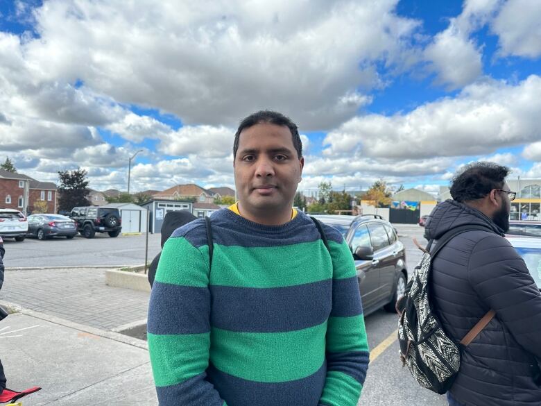 Edgar Xavier in a green and blue stripe sweater outside the BLS office.