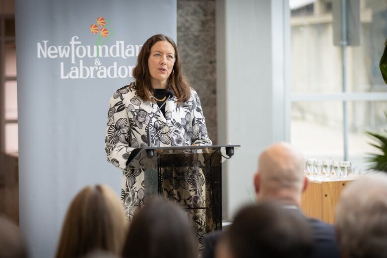 Woman standing at a podium in front of a sign that says Newfoundland and Labrador.