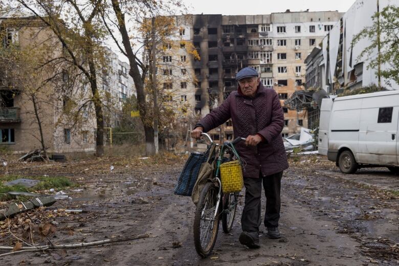 A man pushes a bicycle near a group of damaged buildings in Avdiivka, Ukraine.