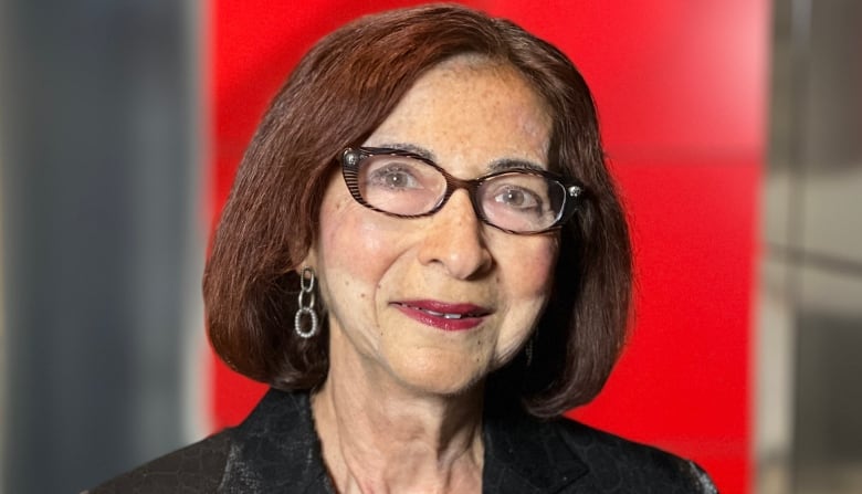 A portrait of a woman with glasses gazing into the camera.