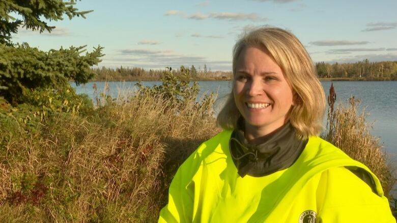 Tonya Wimmer smiles during an interview with a lake behind her.