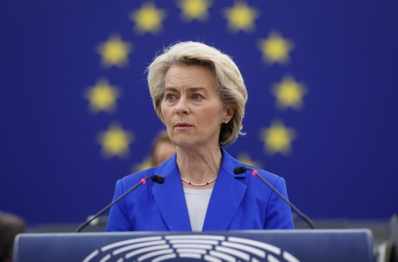 A woman in a blue jacket stands behind a podium.