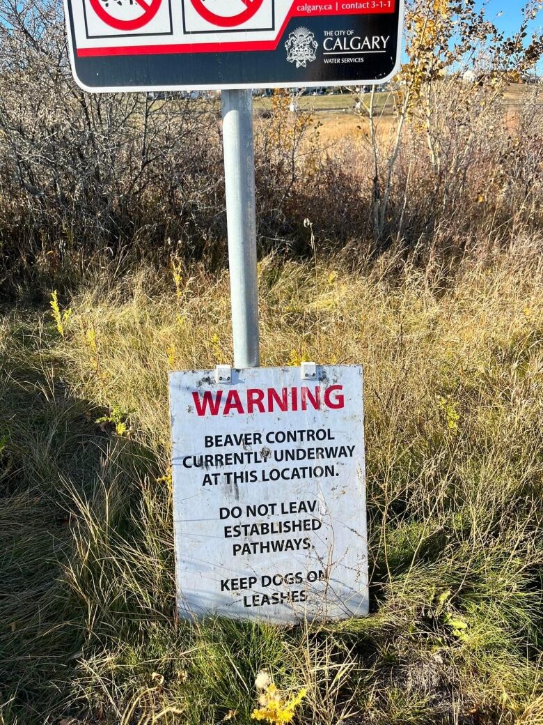 A warning sign stands in high grass.