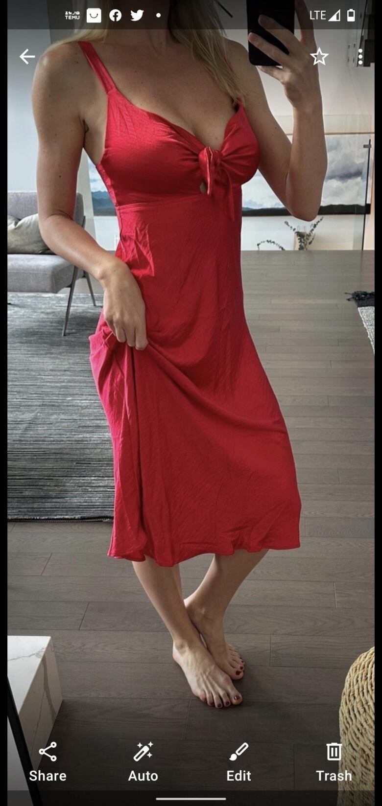 A screengrab of a mobile phone with a neck-down selfie of a woman in a red dress