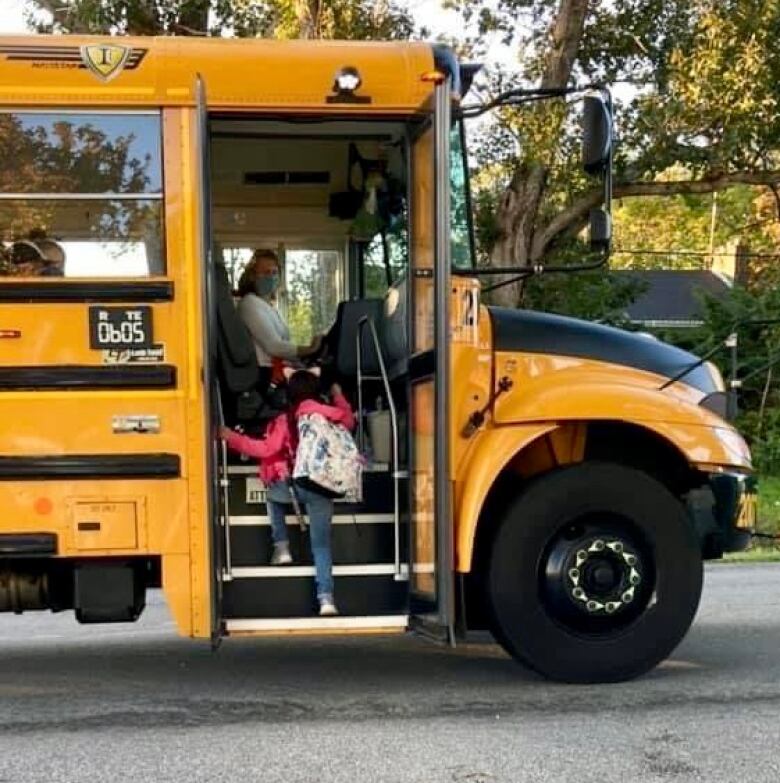 A child steps on to a yellow school bus.