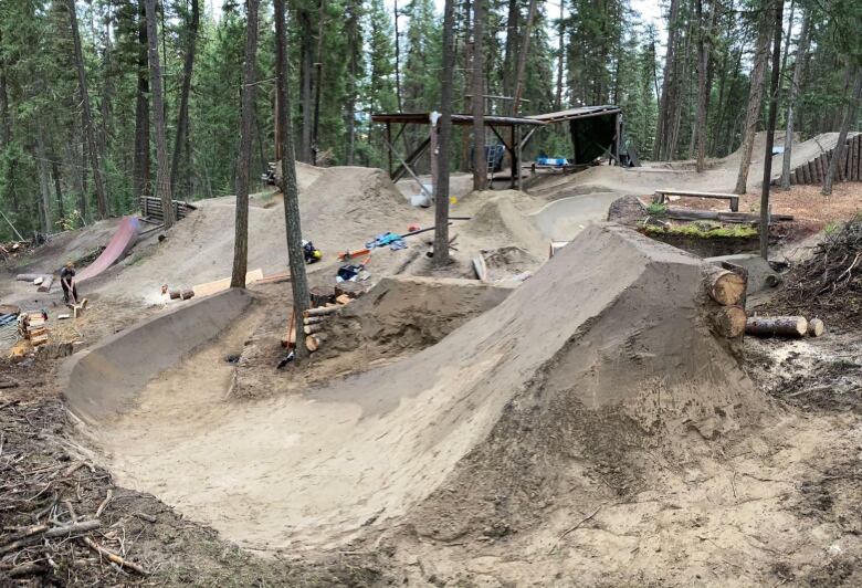 A dirt bike track runs through a wooded area with various tools laying about.