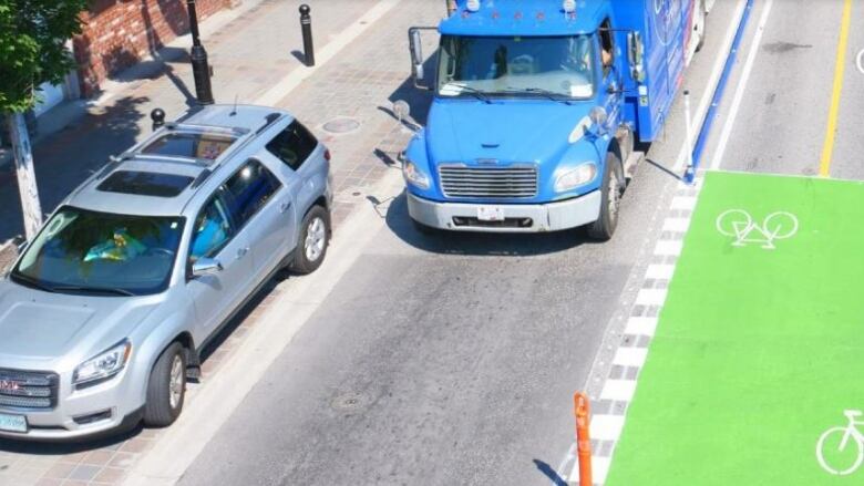 A bike lane, with green paint and white bicycle stencils, is shown in a downtown area.