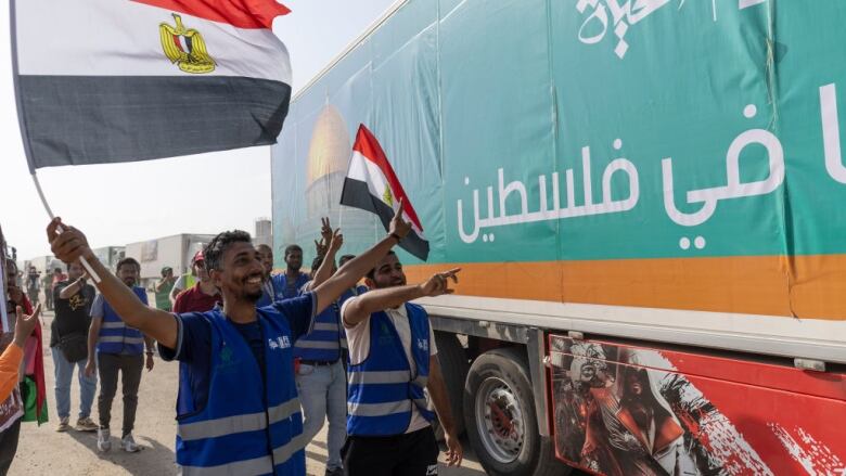 People wave Egyptian flags near a truck carrying humanitarian aid.