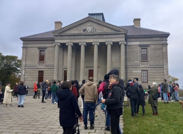 About 100 people standing in front of neoclassical building