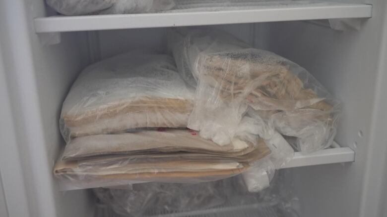 A pile of papers in a plastic bag sitting on the shelf of a freezer