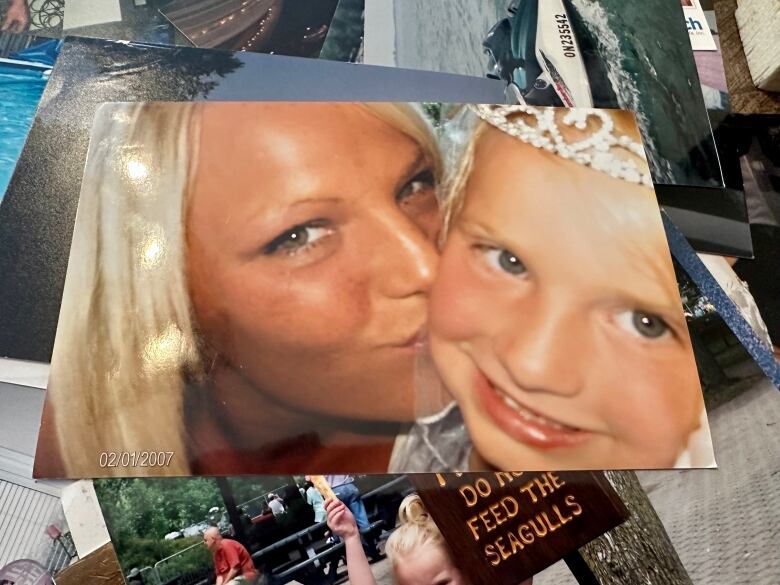 A blond woman kisses a little girl who's smiling in this photo of a family photo.