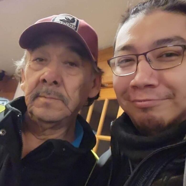 A father and son smile at the camera.