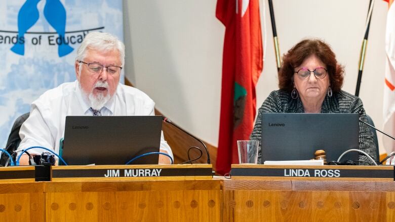 A man and a woman sit beside each other at a conference table.