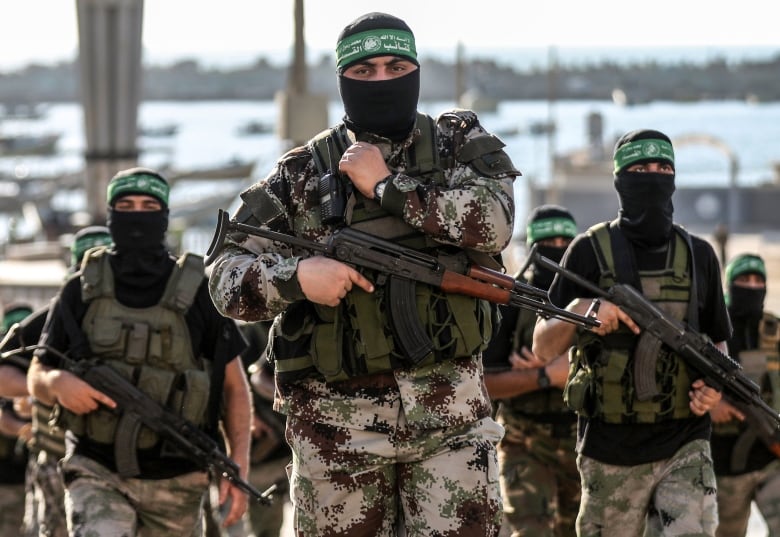 Armed men wearing green headbands and black face coverings.