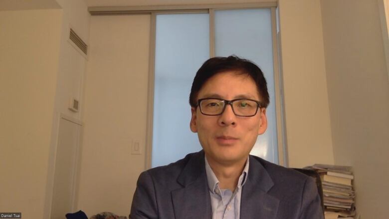 A man in a room with books in the background