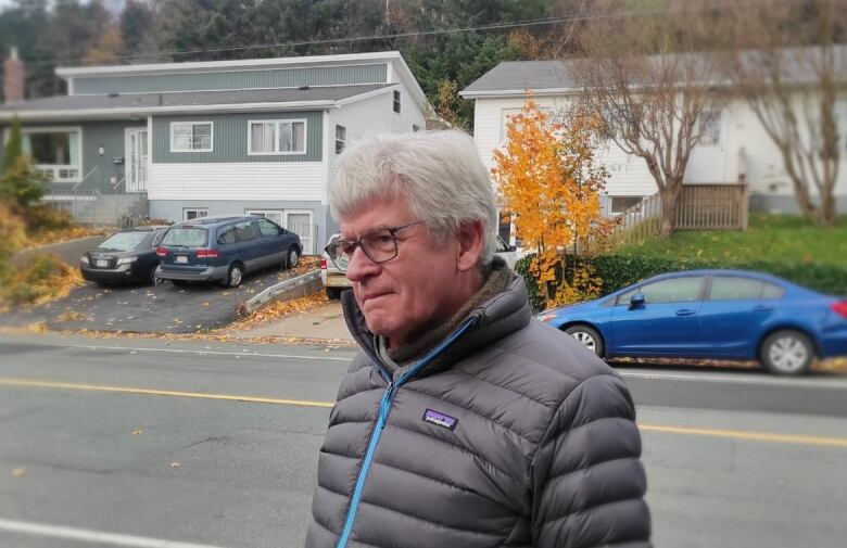 Man with glasses and a gray coat standing in the street