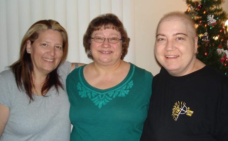 Three women smile for a picture. 