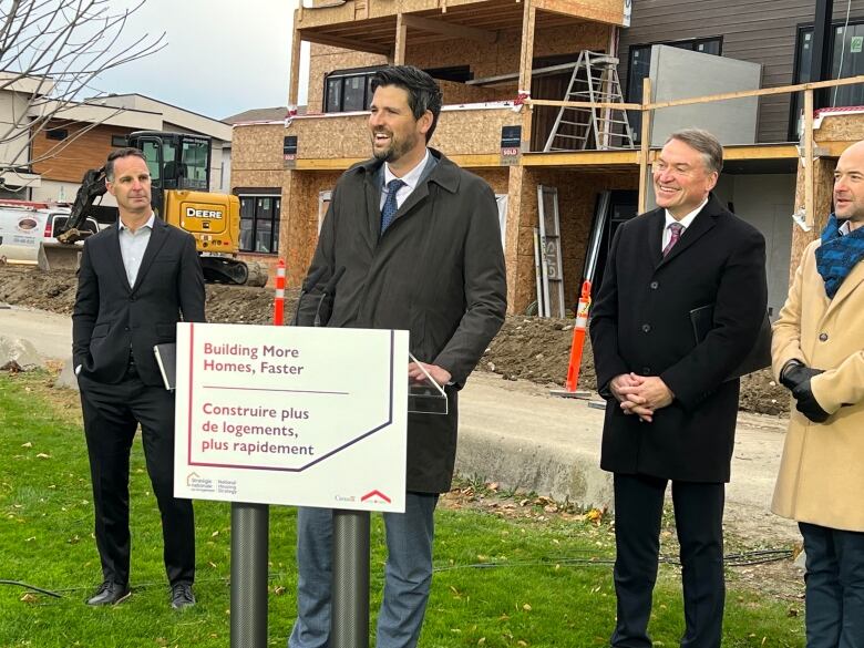 Federal Housing Minister Sean Fraser standing at a press conference in Kelowna, B.C. on Wednesday in front of a housing construction project along with members of city council