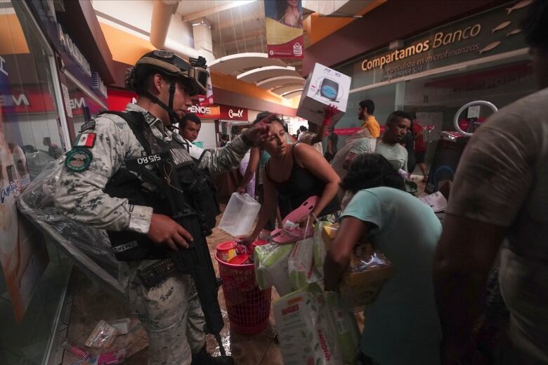 A soldier with a rifle tries to stop looting at a shopping mall.