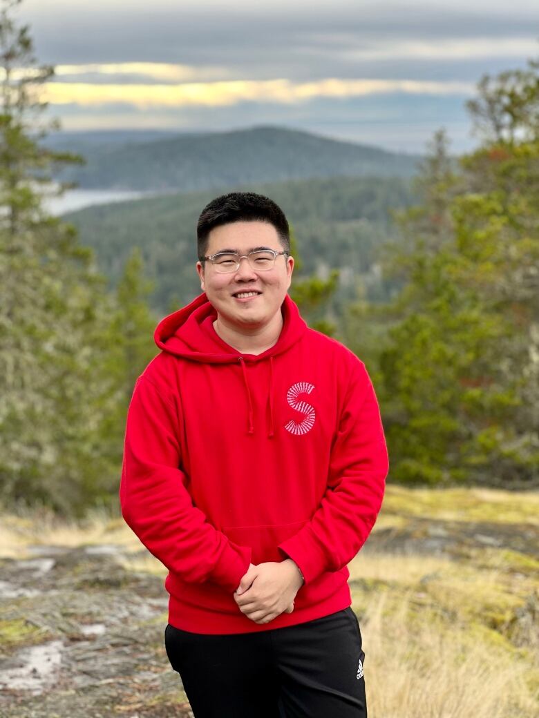 A man wearing a red hoodie smiles