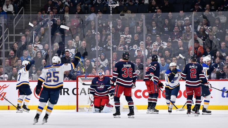 St. Louis Blues celebrate after scoring a goal, with fans in the stands in the background.