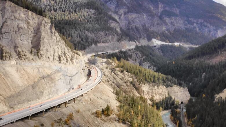 A stretch of paved highway appearing in its near-completion stage is seen off the side of a mountain. 